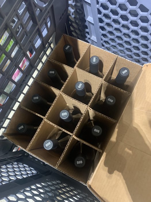 En öppen låda med flera flaskor chardonnayvin som har kraftig vaniljsmak.