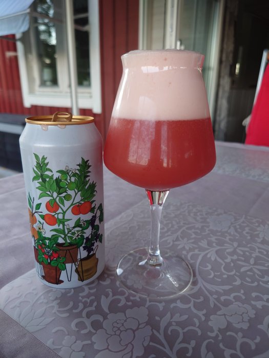 Burk med konstnärlig design bredvid ett glas fyllt med rosa skummande dryck på blommönstrad duk.