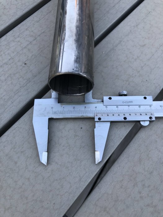 Skjutmått mäter diametern på ett rör mot en träbakgrund.