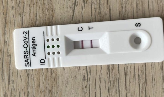 Covid-19 antigentest med ett positivt resultat visas på en träyta.