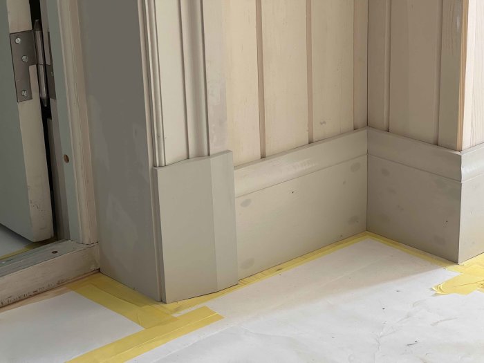 Hörn av rum med nyinstallerade snickerier och lister, förberett för spackling och målning.