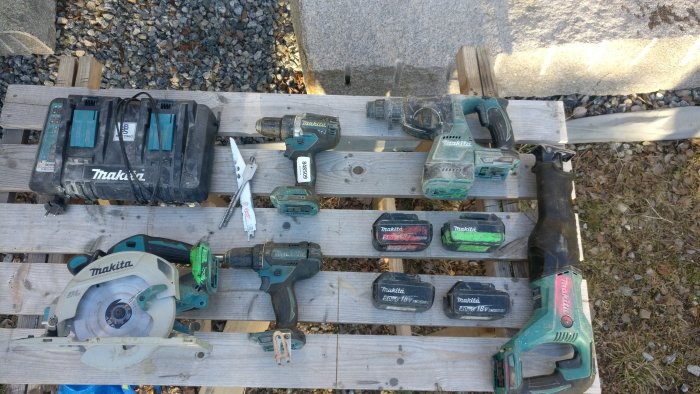 Begagnade Makita-verktyg, inklusive batterier, skruvdragare och cirkelsåg, på en träpall.