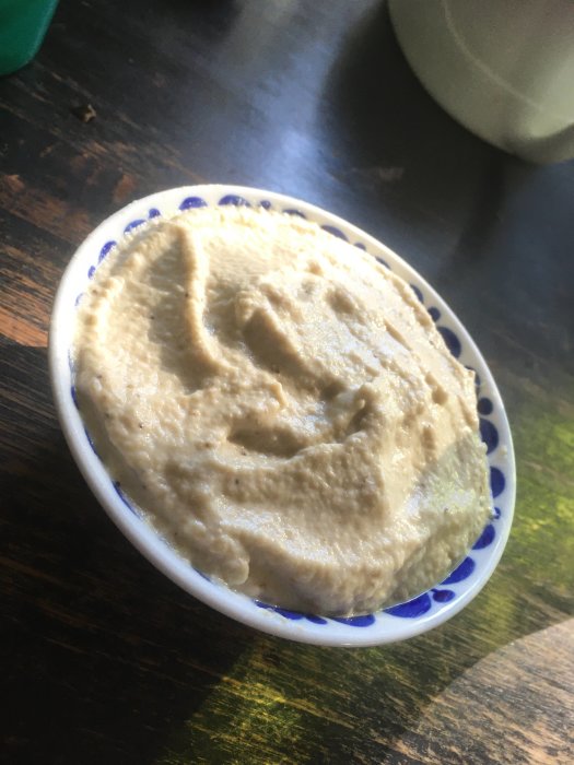 Hemlagad baba ganoush i en vit och blå skål på ett mörkt träbord.