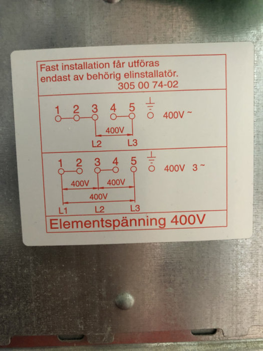 Etikett på elinstallation med scheman för elementspänning och varningar om behörig elinstallatör.