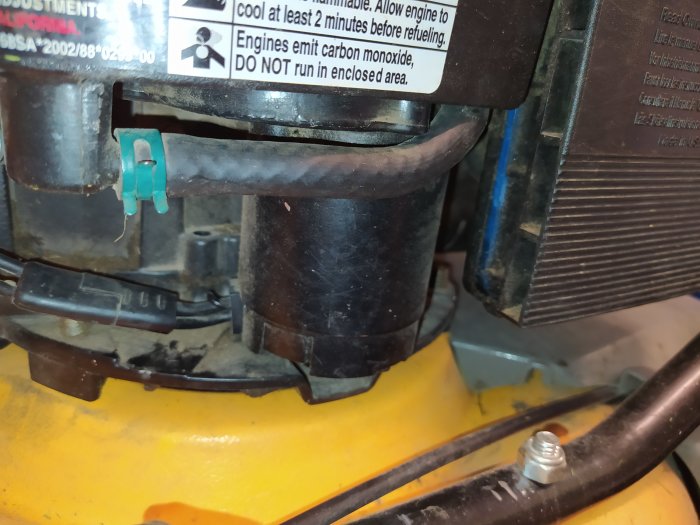 Del av maskin med etiketter, troligen startmotor, och svart relä mot gul bakgrund.