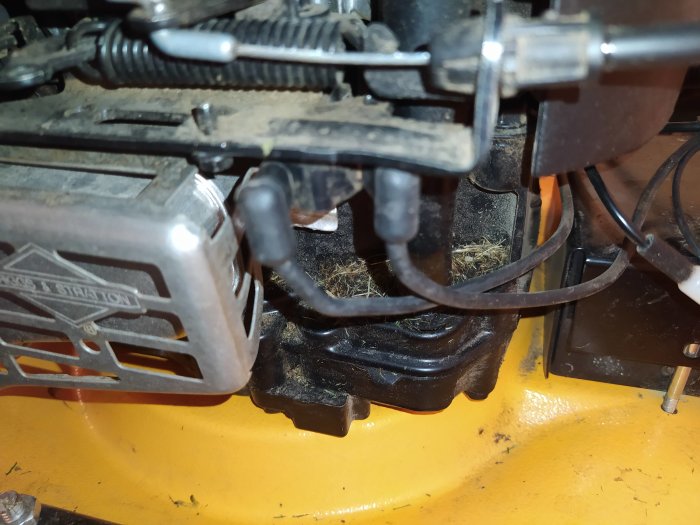 Del av motor med Briggs & Stratton-logotyp och synliga kablar på gul botten.