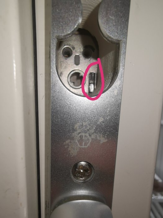 Närbild på en dörrlåsmekanism med en markerad trasig del inuti.