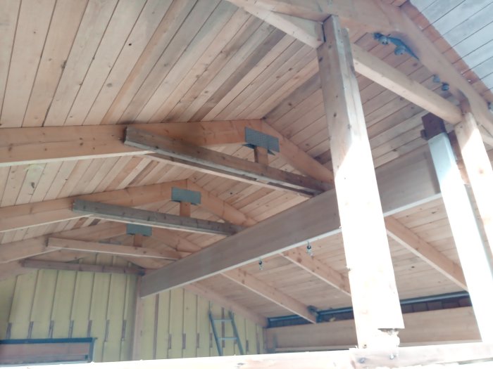 Katto keskeneräisessä puutalossa, jossa näkyy puupalkkeja ja kattorakenteita.