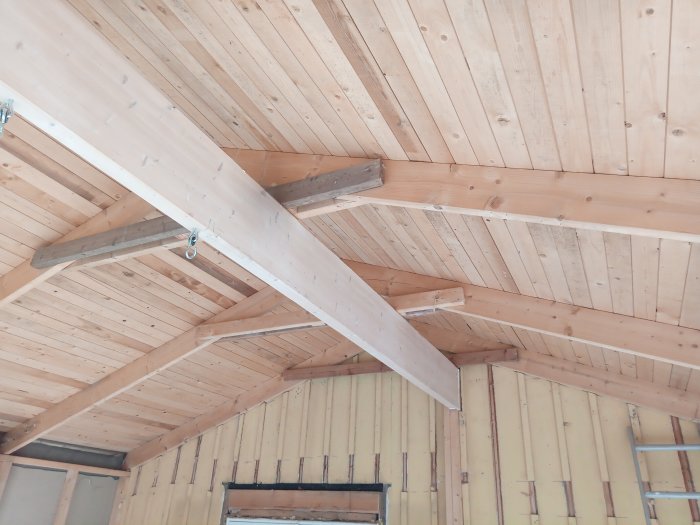 Puinen kattorakenne, jonka tukipalkit ovat esillä remontoitavassa rakennuksessa.