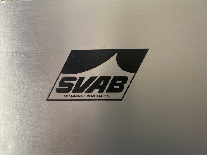 Logotyp för SVAB Skänninge Ventilation på en metallisk yta.