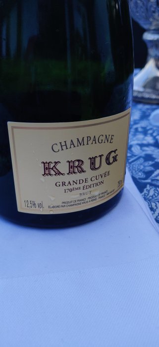 Flaska av Krug Grande Cuvée Champagne på ett dukat bord.