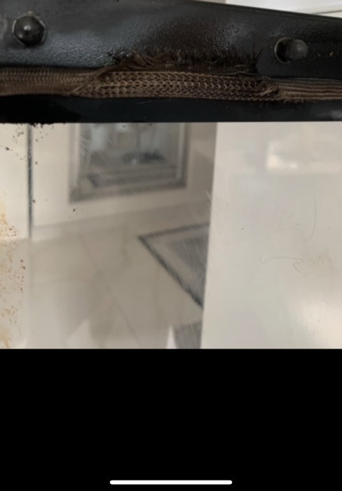 Skadad tätningslist och sprickor nära fönsterglas med synliga tecken på läckage och slitage.