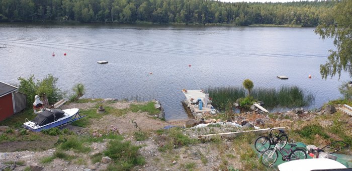 Vy över tomt med brygga, båt och insjö, tagen från ett hus.