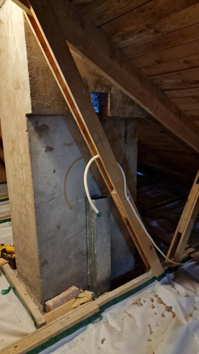 Ventilationsaggregat under installation på vind med isolering, rörgenomföring, och trästöd.