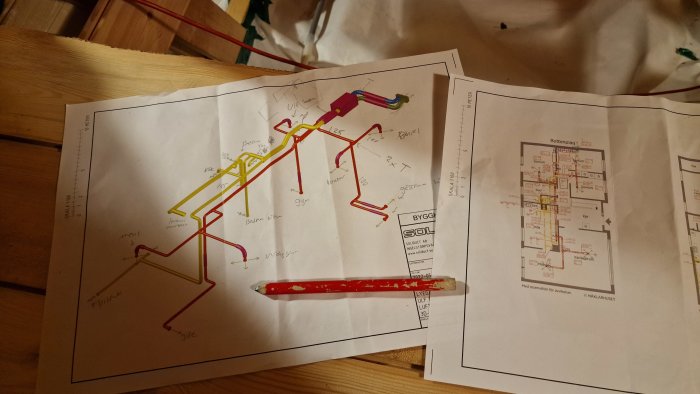 Ritningar markerade med färg från ett byggprojekt, inkluderar anteckningar och ett suddigt verktyg.