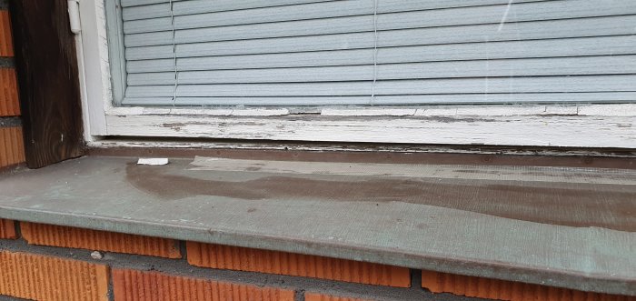 Nedslitet fönsterfoder och fönsterbräda med färgflagning och mögel.