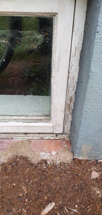 Närbild av ett fönster med slitet karm och fönsterbleck som behöver renovering.