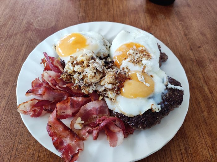 En tallrik med stekt ägg, bacon och köttbullar som frukostkoncept.