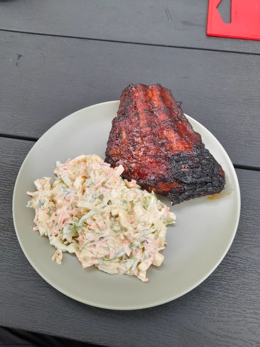 Grillad BBQ-fläskkotlett och coleslaw på en tallrik utomhus