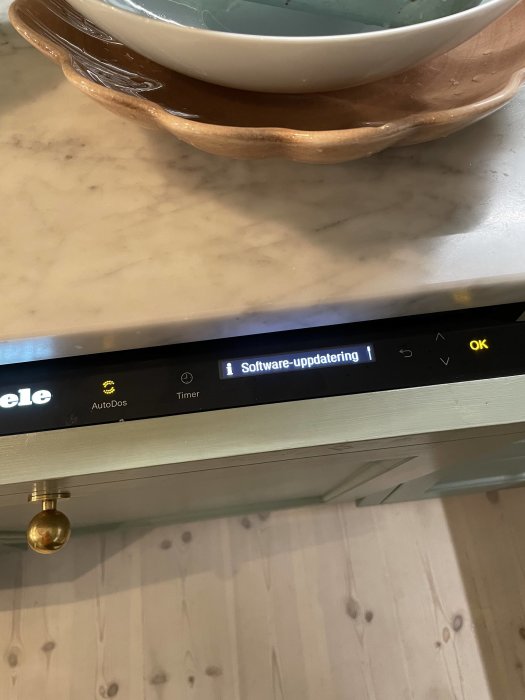 Slät marmor bänkskiva med en diskmaskin ifrån Miele som visar meddelandet "Software-uppdatering" på displayen.