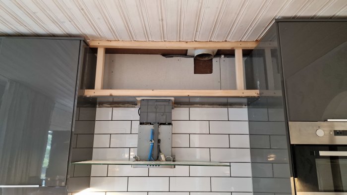 Kök med ny ventilation: kanal genom murstock, imkanal ansluten till spisfläkt ovanför kakel och hyllor.