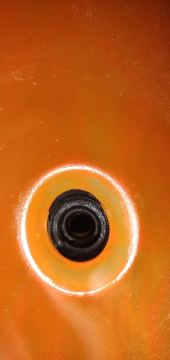 Närbild av ett 1.2cm borrhål i en orange yta med en svart insida.