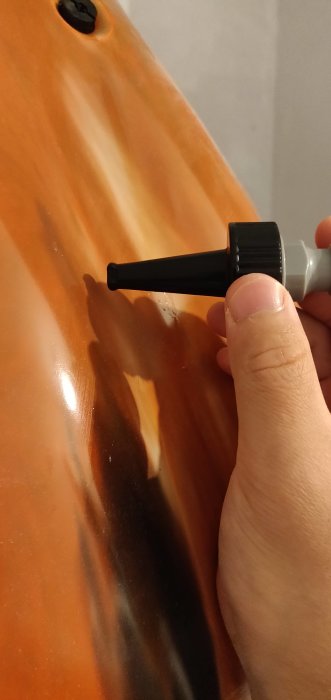 Person håller en mätpinne mot ett orange-brunt föremål för att mäta diameter.