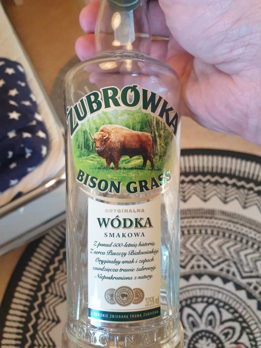 Hand håller en flaska Żubrówka Bison Grass vodka med etikett och bild av en bison.