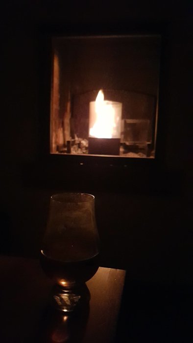 Ett glas Tamnsvulin framför en etanolkamin med flammande eld inuti en öppenspis.