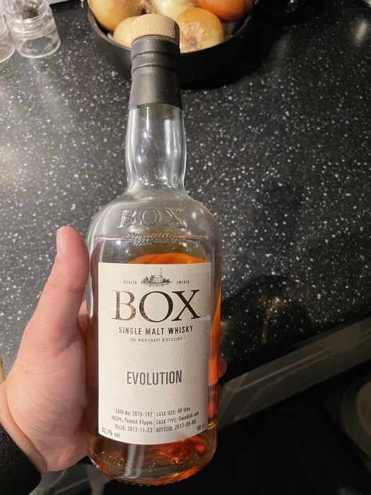 Hand håller en flaska BOX Single Malt Whisky med etiketten ‘Evolution’ från The High Coast Distillery.