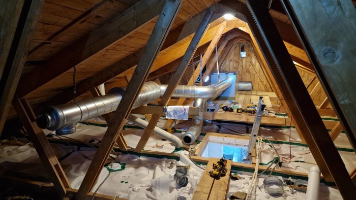 Vind med ventilationskanaler under installation, verktyg och byggmaterial syns.