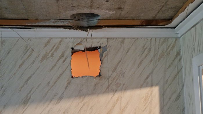 Ett hål i en vägg med synlig råspont och tillfällig reparation med orange konstruktionsduk.
