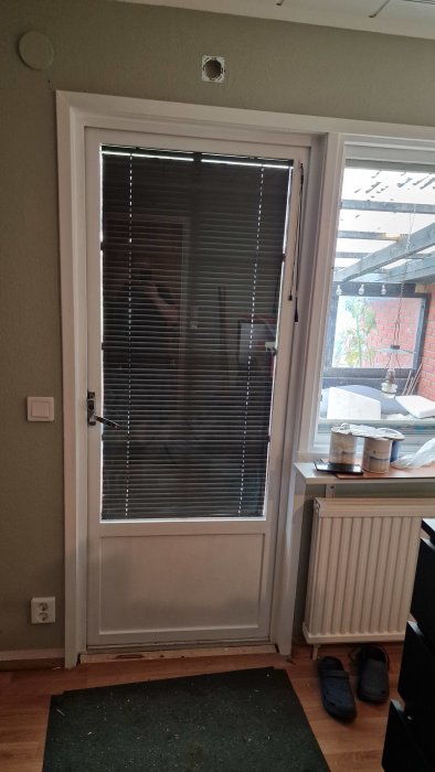 Nyinstallerad begagnad altandörr med persienner i ett renoverat hem.