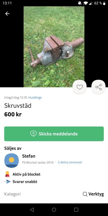 Begagnad skruvstäd på gräs, rostig med synliga bruksspår.