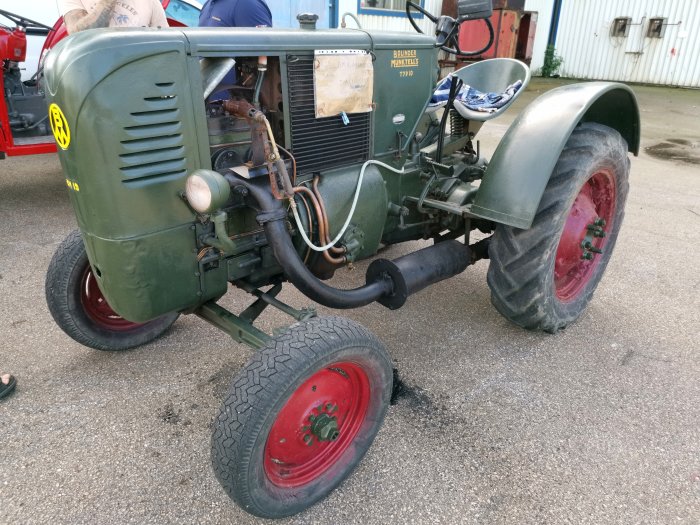 Gammal grön traktor med röda hjul från Bolinder-Munktell, parkerad utomhus.