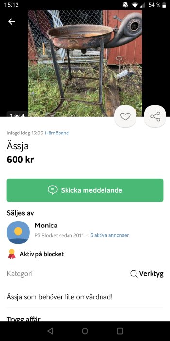 Rostig gjutjärnsgryta på ben med en gammal traktordel monterad som handtag.