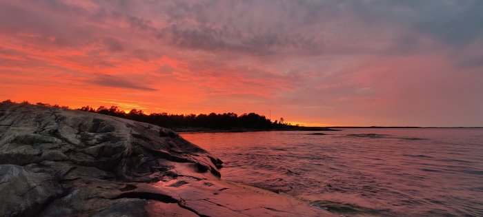 Dramatisk solnedgång med röd himmel över klippor och hav på Torrö.