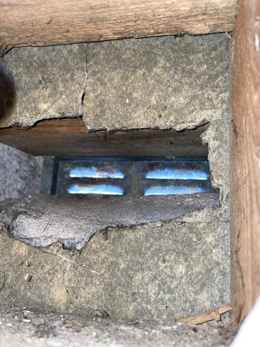 Vy genom spricka i sten vid en byggplats som visar gaslågor från en värmekälla.