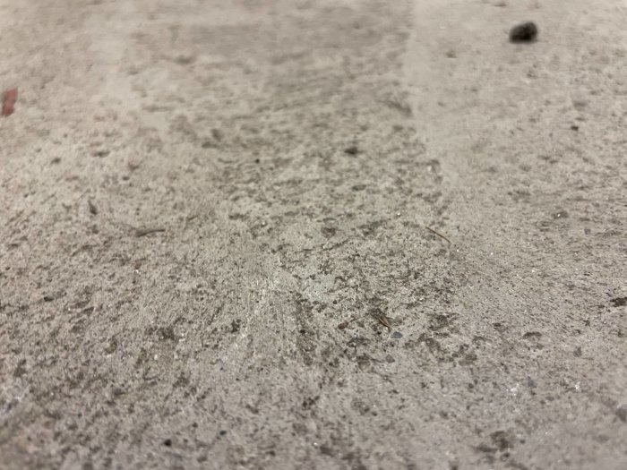 Närbild av en grov betongyta med tydliga korn och små skräp.