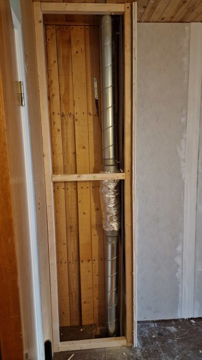 Installation av flexdämpare i bjälklag, omgiven av trästomme och isolering, i en byggmiljö.