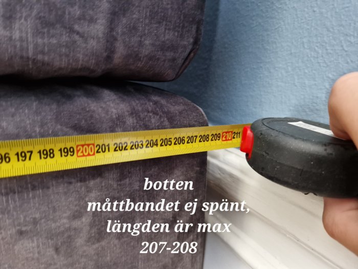 Mätning av ett soffdjup med ett måttband som visar maxlängden, ungefär 207-208 cm.