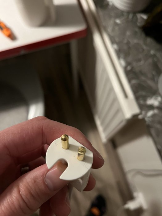 Hand håller en bränd Ikea ojordad kontakt med synliga skador.