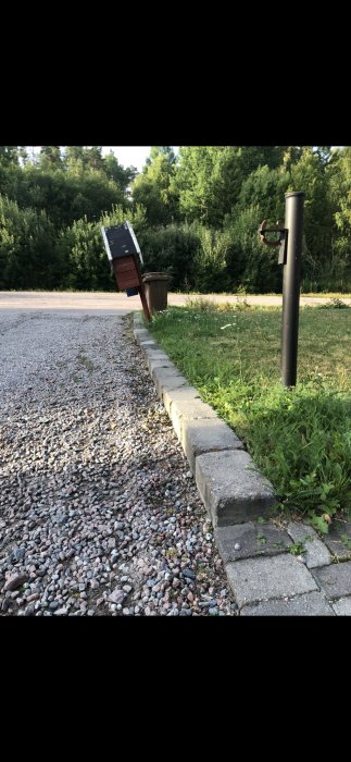 Stenkant som avgränsar grus från grannens gräsmatta, stenar tryckts ut av ställning.