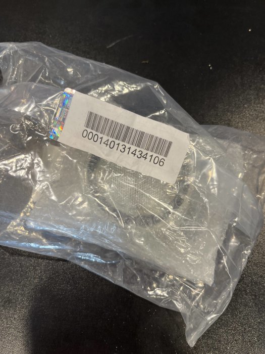 Sprucken lampa i plastförpackning med synlig streckkod.