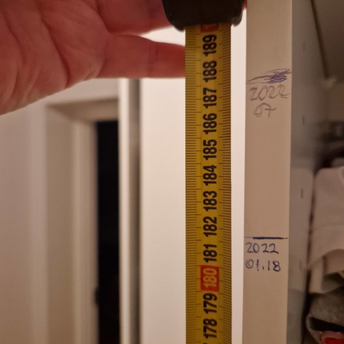 Måttband visar längden 187 cm på en väggmarkering, symboliserar tillväxt av en tonåring.