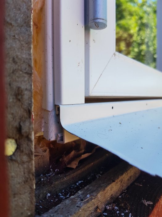 Närbild på fönsterinstallation med synlig isolering och ojämnt avslut mot husvägg.