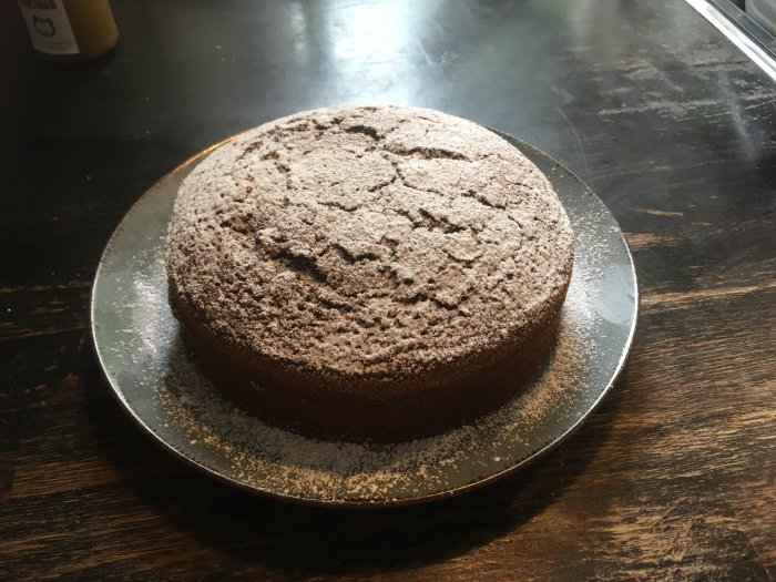 Hemlagad Kalle Ankaka-kaka pudrad med florsocker på ett serveringsfat, på ett mörkt träbord.