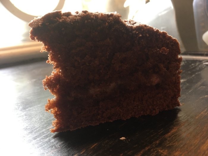En bit mörk Kalle Anka-kaka på en bordsskiva med mörk bakgrund.