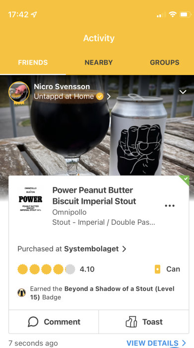 Ölglas fyllt med mörk stout och en burk Power Peanut Butter Biscuit Imperial Stout på ett träbord.
