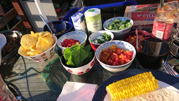 En middag bestående av tacos med egenodlade grönsaker och majs serveras vid ett bord utomhus.